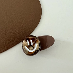 Close-up of coffee brown marble texture hair clip with white smiley face pattern
