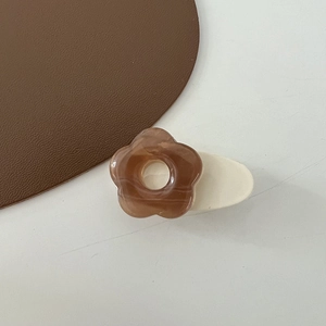 Detail of coffee-colored amber flower hair clip with smooth acetate texture and white base