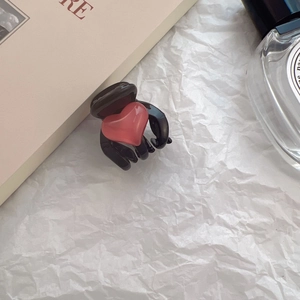Detail view of small black hair claw clip with red heart on aesthetic white background