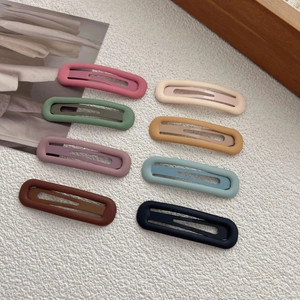 Set of 8 minimalist matte oval hair clips in pastel colors on a textured white background