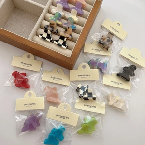 Mini pinces à cheveux en acétate aux motifs variés sur un fond blanc épuré