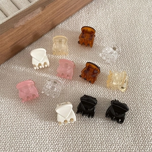 Flat lay of colorful mini hair clips on fabric, including white, pink and amber colors