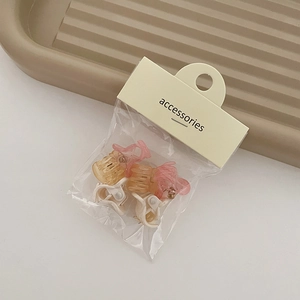 Detail of mini hair claws in orange and beige tones on an elegant striped tray