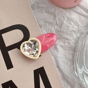 Détail de la pince à cheveux cœur rose avec strass sur carte décorative
