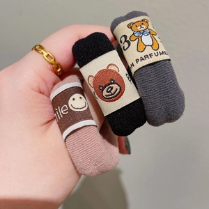 Close-up of knit hair ties in pink, black, and gray featuring bear and smile embroidery