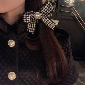 French vintage houndstooth bow hair tie with large pearl worn on a model side ponytail