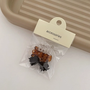 Set of 6 mini plastic hair claws in black, amber, and clear on beige card packaging