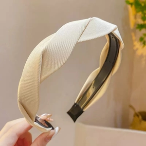 Detailed macro view of beige twisted fabric headband with internal anti-slip teeth