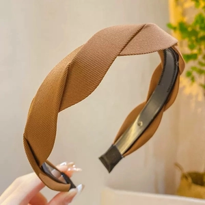 Detail of a brown twisted headband with ribbed fabric texture and non-slip inner teeth