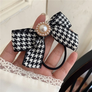 Detailed close-up of houndstooth bow hair tie with vintage pearl embellishment