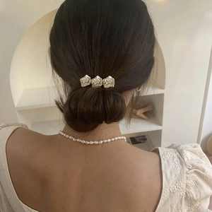 Elegant camellia hair clip with pearls worn by a woman with a classy updo hairstyle