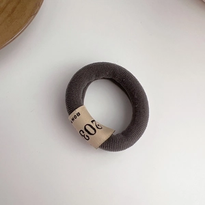 Detailed view of dark grey striped fabric hair tie with vintage numeric woven label