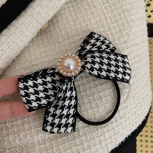Detail of houndstooth bow hair tie with pearl accent and elastic rope in French style