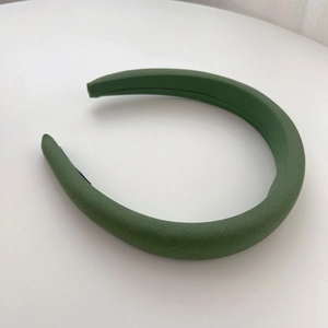 Close-up of thick dark green sponge headband with textured fabric and wide design