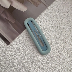 Detail view of a matte mint green oval hair clip on a textured white fabric background