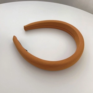 Detailed macro view of the thick bright orange padded headband with textured fabric finish