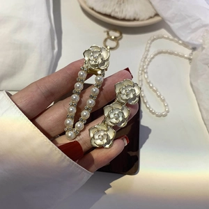 Detailed view of camellia hair clips with faux pearls and gold finish on white fabric