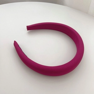 Detail of rose red padded fabric headband showing smooth texture on white background