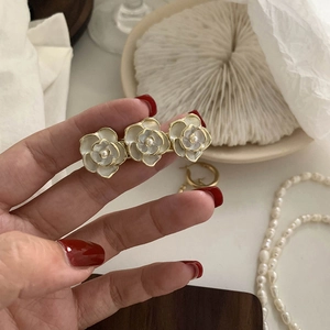 Detail of three white enamel camellia flowers with pearls on a golden hair clip