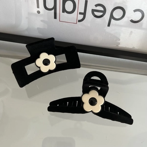 Detail of black velvet hair clips with daisy flower accents on glass surface