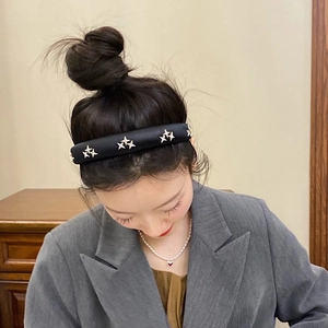 Padded black satin headband with gold star accents worn by a female model in casual style