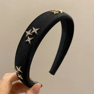 Detail of black padded headband with sparkling rhinestone stars on satin texture