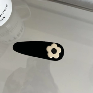 Close-up of black velvet BB hair clip with a cute cream floral accent for daily styling