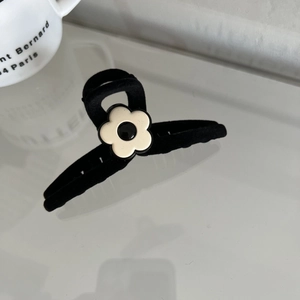 Close-up of black velvet hair claw clip with white cream flower detail for women