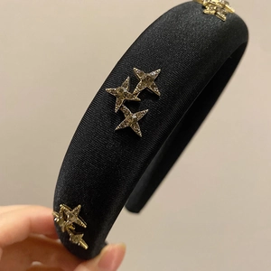 Detail of black sponge headband featuring gold star ornaments with sparkling rhinestones
