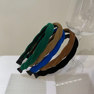 Détail de bandeaux torsadés en velours vert, bleu, kaki et noir sur un verre à vin