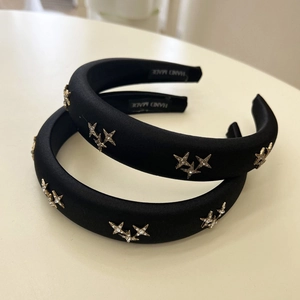 Detail of black padded headband featuring golden star studs and handmade woven label