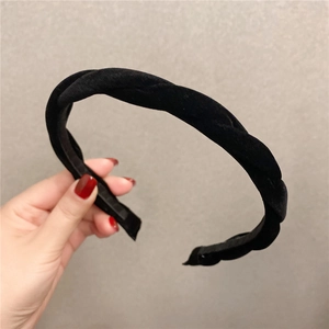 Détail d'un serre-tête en velours noir à texture tressée et design large épais
