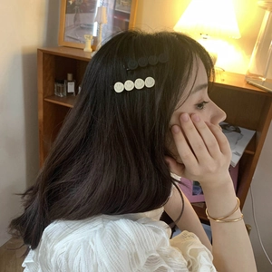 Chic smiling face side hair clips in black and cream worn by model in a cozy setting