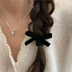 Detail of black velvet bow hair tie styled on a braided hairstyle for a chic look