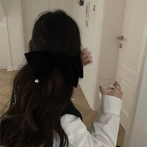 Détail d'une élégante pince à cheveux nœud en velours noir avec perle blanche