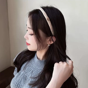 Detail of a knitted beige headband with a brown leather rabbit patch on a female model