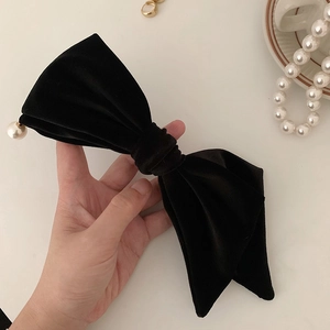 Détail d'une grande pince à cheveux nœud en velours noir avec un pendentif perle blanche