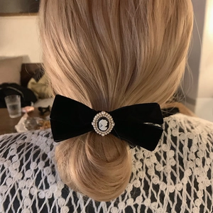 Detailed view of a vintage black velvet bow hair tie with a cameo and pearl charm
