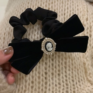 Detail of vintage black velvet bow hair tie featuring an oval lady relief and pearl trim