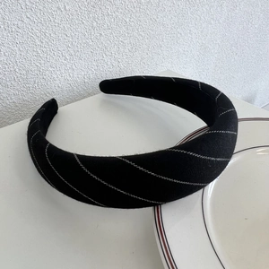 Close-up of black plaid sponge headband with silver stitch details for a high skull top