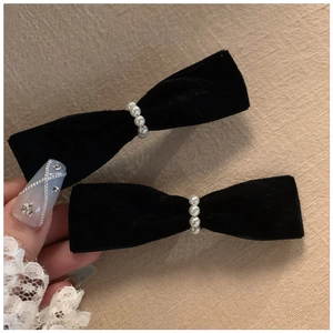 Close-up of black velvet bow hair clips with white pearl centers in a vintage style