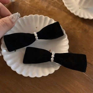 Pair of vintage black velvet bow hair clips with pearls on a decorative shell plate