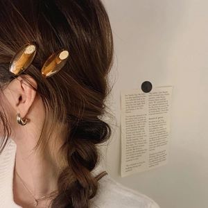 Amber oval hair clip and gold metal earrings set on woman in minimalist style