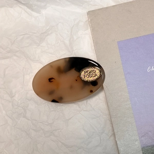 Détail d'une barrette en acétate écaille de tortue avec plaque métallique dorée gravée
