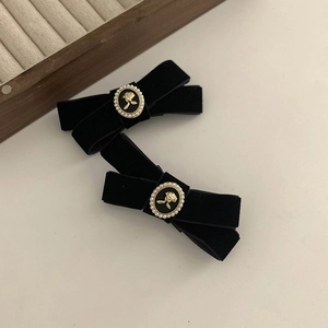 Close-up of black velvet bow hair clip with gold relief rose and pearl center detail