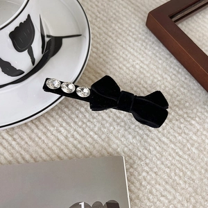 Elegant black velvet bow hair clip with sparkling rhinestones on beige knit backdrop