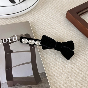 Close-up of black velvet bow hair clip with three sparkling rhinestones on fabric