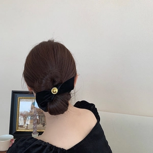 Elegant black velvet bow hair scrunchie with gold metal buckle on a woman's hair bun