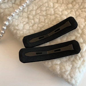 Elegant pair of black velvet rectangular hair clips with rhinestones on soft white fabric
