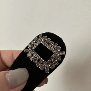 Détail macro d'une pince à cheveux en velours noir avec strass carrés de luxe